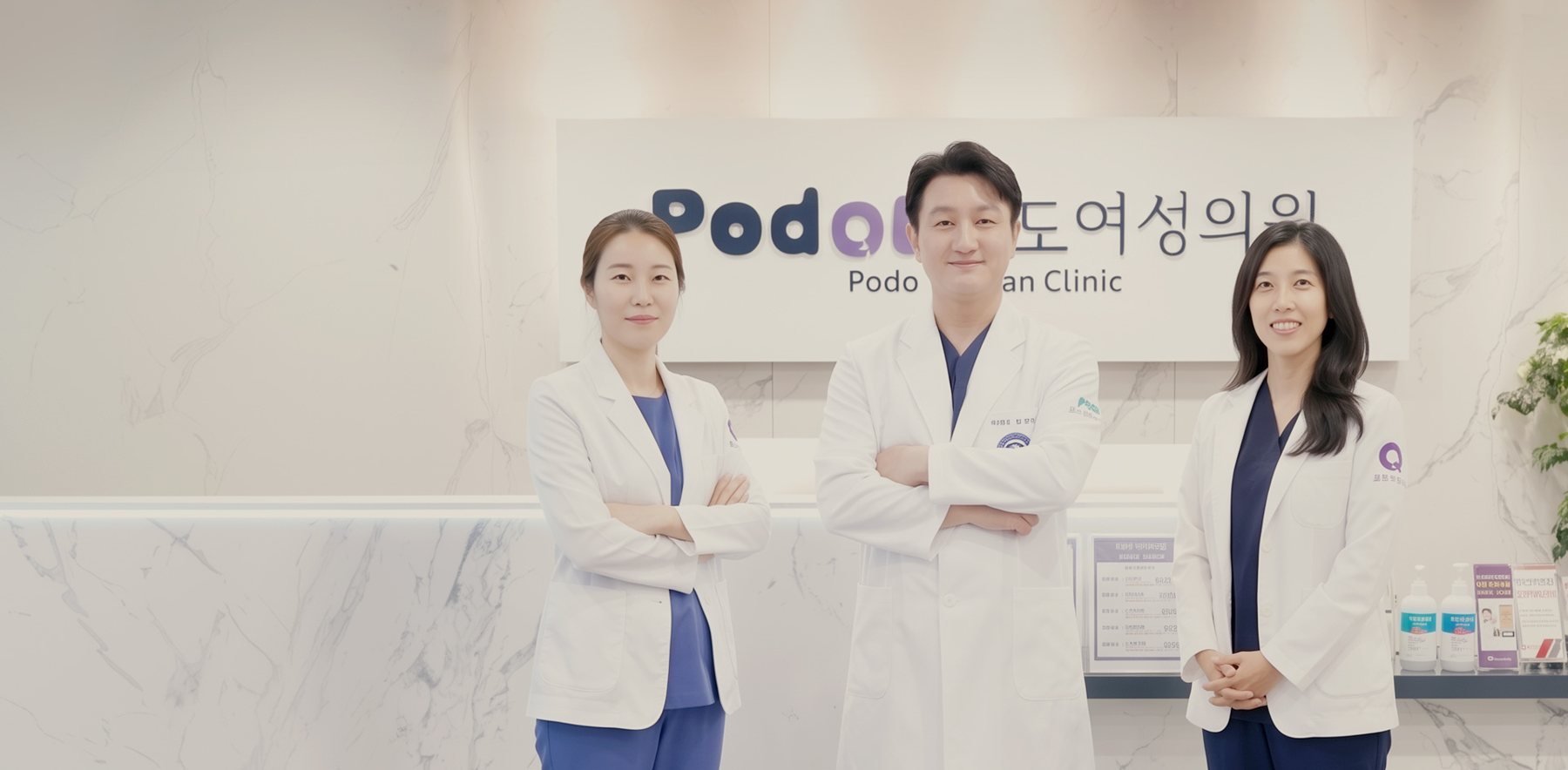 포도여성의원 로고 벽 앞에 선 의료진 3명
