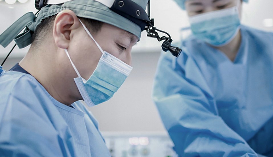 헤드라이트·마스크를 쓰고 수술에 집중하는 의사 클로즈업