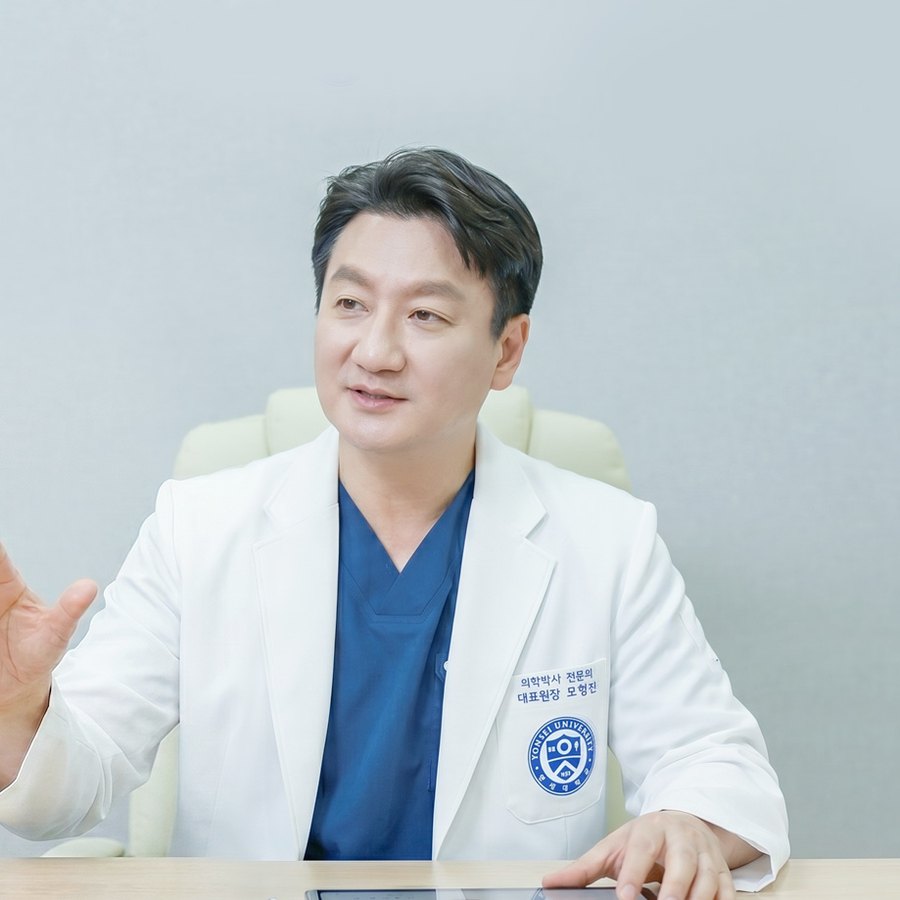 진료실 책상에서 손짓하며 설명하는 모형진 대표원장