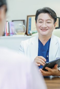 태블릿을 들고 상담하며 웃는 대표원장