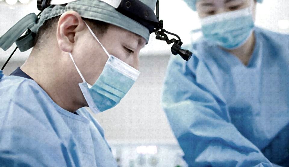 헤드라이트·마스크를 쓰고 수술에 집중하는 의사 클로즈업